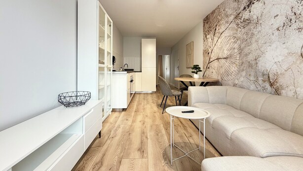 Una sala de estar moderna con un sofá, una mesa de centro y un comedor con mesa y sillas.