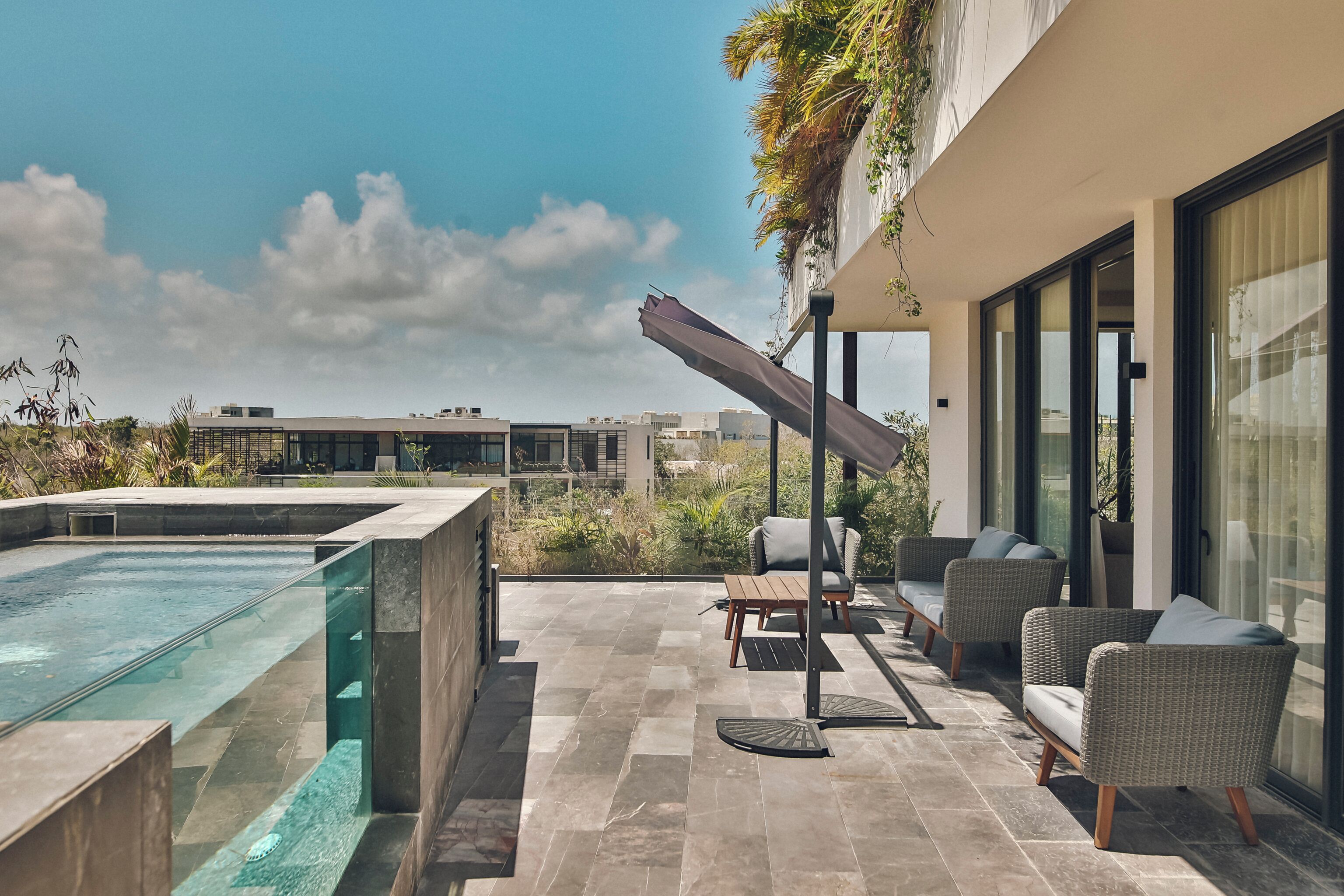 A rooftop terrace with a swimming pool, outdoor seating, and a view of the cityscape.