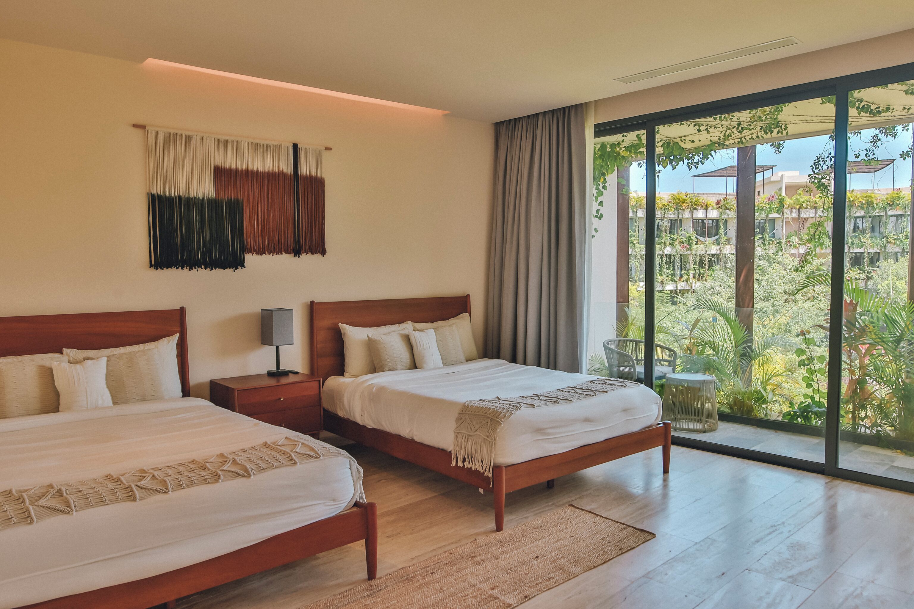 Ein Hotelzimmer mit zwei Betten, einem großen Fenster mit Blick auf Grünflächen und einem modernen Design.