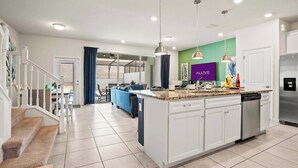 Een moderne keuken met witte kasten, een centraal eiland, roestvrijstalen apparatuur en hanglampen.