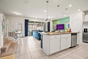 A modern kitchen with white cabinets, a central island, stainless steel appliances, and pendant lighting. - Magical Stay at Windsor Island with pool (Davenport)