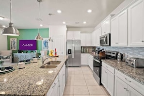 A modern kitchen with white cabinets, granite countertops, stainless steel appliances, and pendant lighting. - Magical Stay at Windsor Island with pool (Davenport)