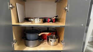 Un armario de cocina con dos estantes, cada uno con utensilios de cocina y una tabla de cortar.