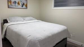 Un dormitorio con una cama, una ventana, un cuadro y un interruptor de luz.