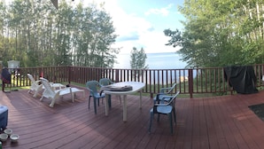 Une terrasse avec coin salon extérieur, un barbecue et vue sur le lac.