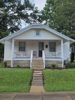 A single-story house with a front porch, a stone foundation, and a number '709' on the front door.