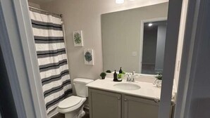 Un baño con inodoro, lavamanos, espejo y cortina de ducha.