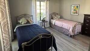 Een slaapkamer met twee bedden, een klein rond tafeltje en een dressoir.