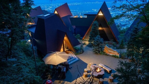 Un complexe hôtelier moderne à l’architecture géométrique, doté d’espaces de détente en plein air et offrant une vue sur la ville.