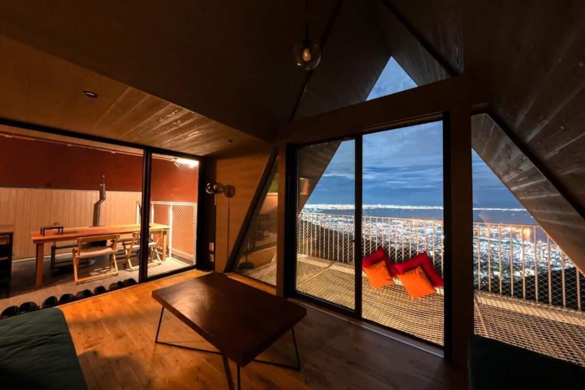 A modern interior with a large window, a wooden table, and a view of a cityscape.