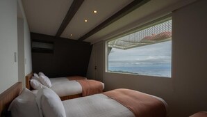 Une chambre avec deux lits, une fenêtre donnant sur un beau paysage et un plafond doté d’un éclairage encastré.