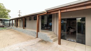 A modern building with a covered patio, a visible kitchen area, and a paved outdoor space.