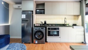 A compact kitchen with a washing machine, oven, and microwave.