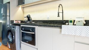 A modern kitchen with built-in appliances, a washing machine, and a countertop with a coffee maker.