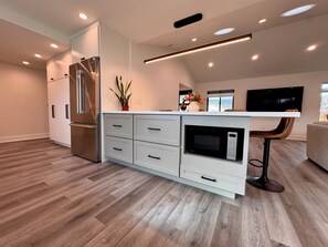 Eine moderne Küche mit weißen Schränken, einer eingebauten Mikrowelle und einem Edelstahl-Kühlschrank.