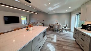A modern kitchen with a marble countertop, integrated appliances, and a dining area with a table and chairs. - New, Quiet, Modern Comfort 3-bedroom house in tranquil Cupertino (Cupertino)