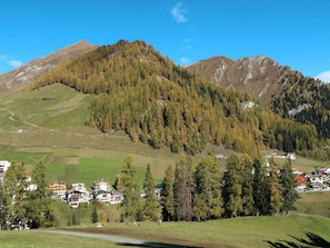 Paisagem montanhosa com uma aldeia, incluindo casas e uma estrada.
