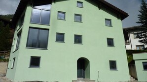 Ein mehrstöckiges Gebäude mit flachem Dach, zahlreichen Fenstern und einem zentralen Eingang.