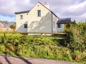 A two-story house with a white exterior, a visible chimney, and a wooden fence in the foreground. - KNOCKNANUSS, family friendly in Ballinascarty, County Cork (Unknown)