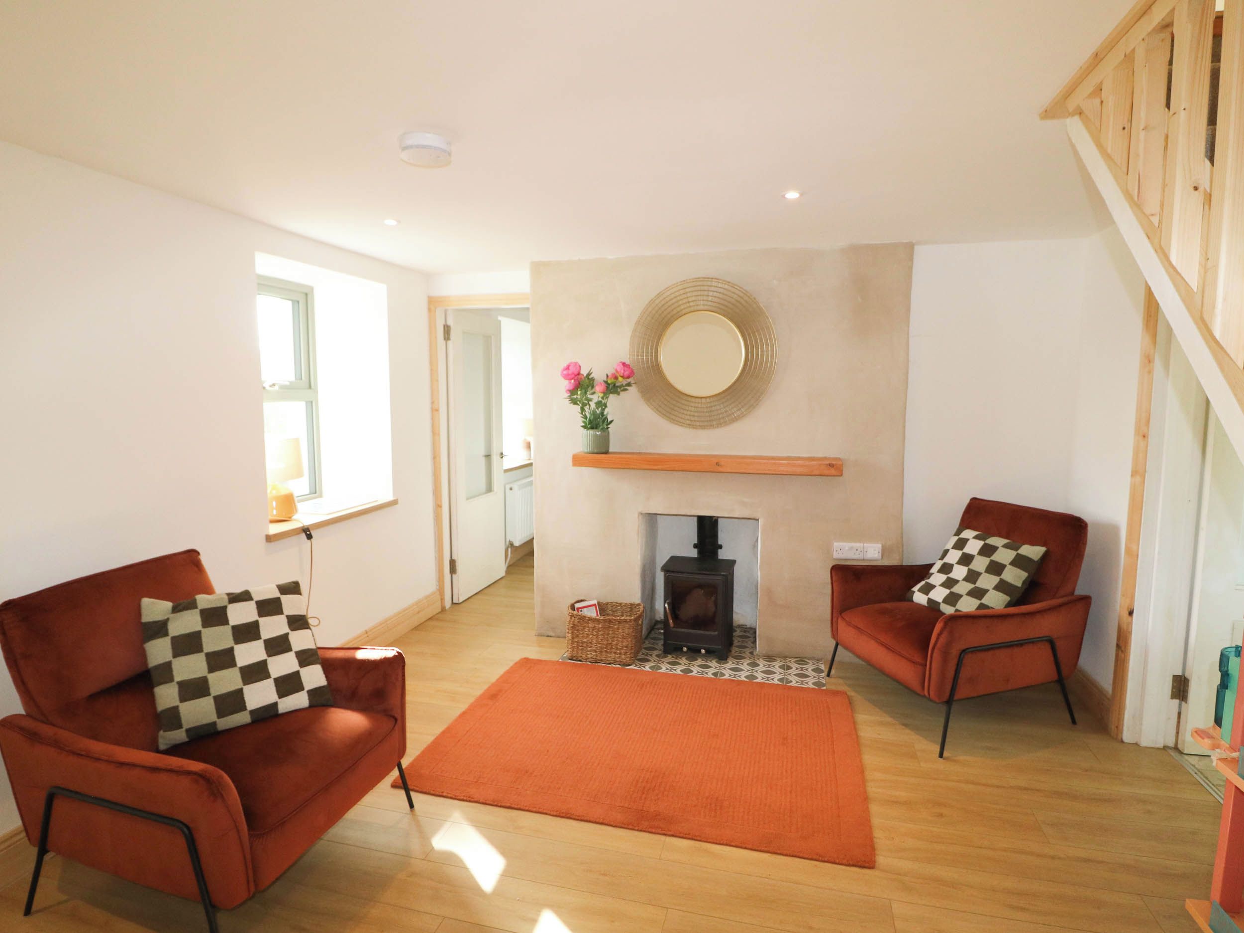 A living room with two armchairs, a fireplace, and a wooden ceiling.