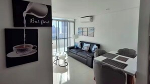 A modern living room with a sofa, a coffee table, and a dining area with a table and chairs. - Spacious 3-bedroom condo in delightful Cartagena with AC and gym (Cartagena)