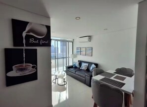 Ein modernes Wohnzimmer mit Sofa, Couchtisch und Essbereich mit Tisch und Stühlen.