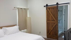 A bedroom with a bed, a ceiling fan, a TV, and a sliding barn door. - Fantastic 4BR Houston Chalet Near NRG, TSU, UofH, & Medical Center (Houston)