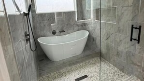 A modern bathroom with a freestanding bathtub, a glass-enclosed shower area, and a marble-tiled floor. - Fantastic 4BR Houston Chalet Near NRG, TSU, UofH, & Medical Center (Houston)