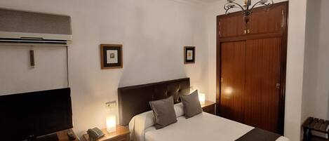 A bedroom with a bed, a TV, a wardrobe, and a chandelier.