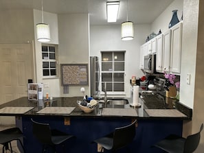 Eine Küche mit Kochinsel, Kühlschrank, Mikrowelle und Spüle.