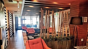 Eine moderne Lobby mit einem roten Sessel, einem Holzpflanzentisch und einer Lampe.