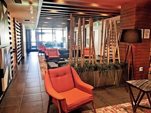 Eine moderne Lobby mit einem roten Sessel, einem Holzpflanzentisch und einer Lampe.