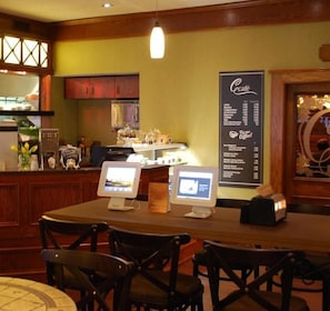Un restaurante con una pizarra de menú, dos monitores de ordenador y mobiliario de madera.