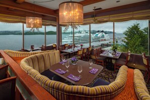 Un comedor con vistas a un crucero, que cuenta con un ventanal grande, muebles de madera y un candelabro.