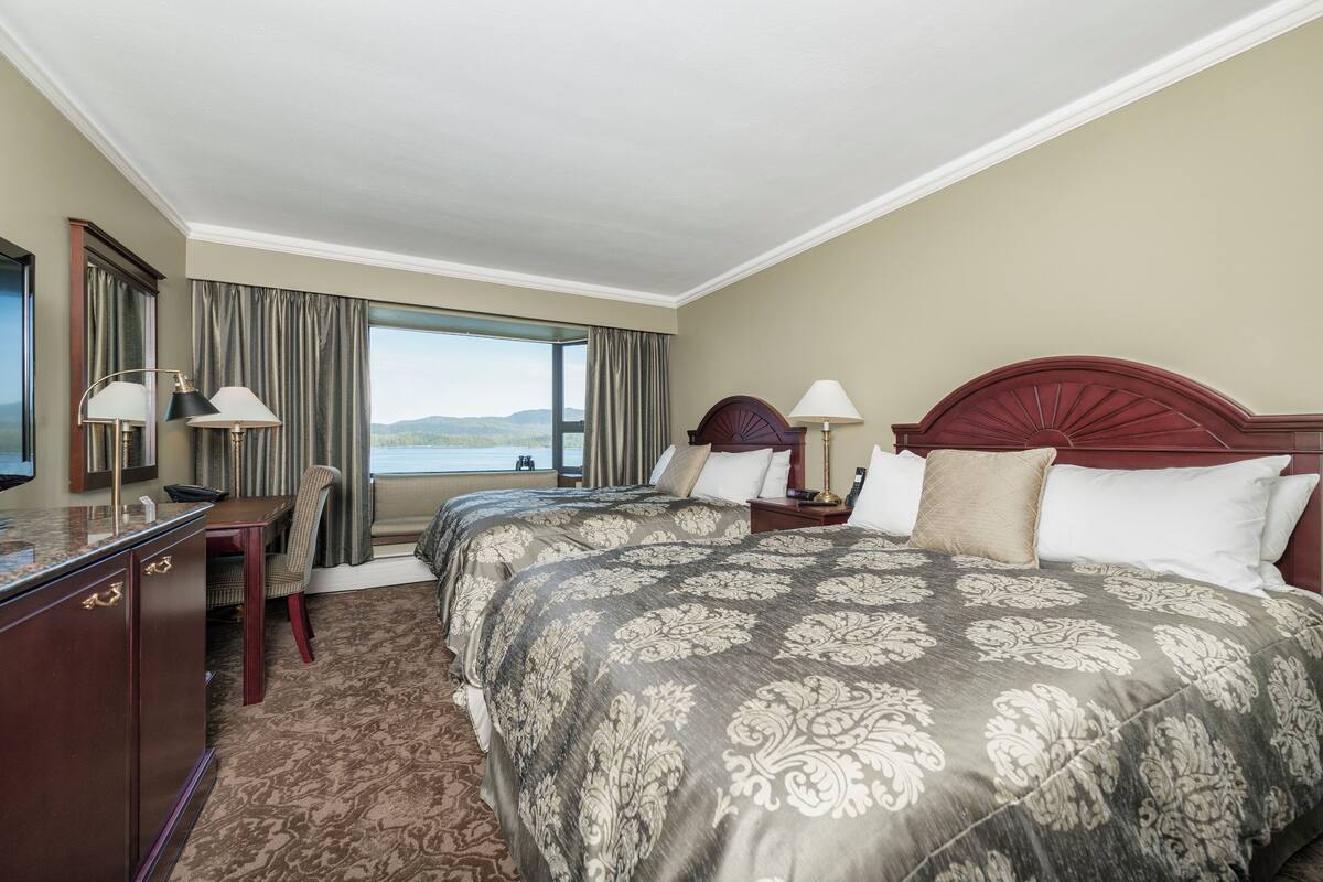 Une chambre d’hôtel avec un grand lit, un bureau, une chaise et une vue sur l’extérieur.