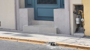 Un edificio con una puerta color turquesa, un pequeño porche y un accesorio de iluminación sobre la puerta.