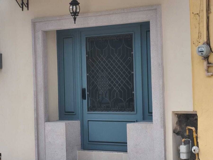 A building with a teal door, a small porch, and a light fixture above the door.