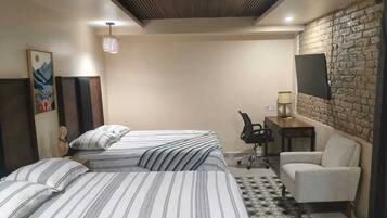 A hotel room with a bed, a chair, a desk, a TV, and a decorative wall.