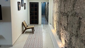 Un pasillo con suelo estampado, un banco, un sofá, una pared de piedra y una puerta que da a otra habitación.