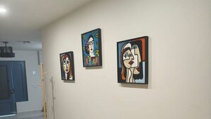 Un pasillo con un banco, tres cuadros enmarcados en la pared y baldosas de suelo estampadas.
