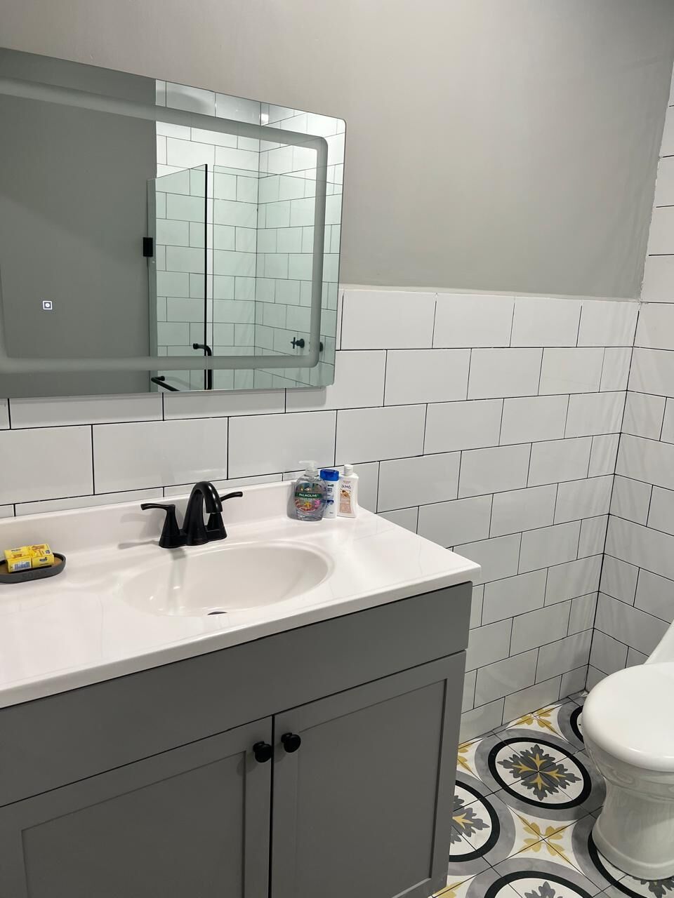 A bathroom with a white sink, a mirror, and a toilet.