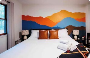 Ein Hotelzimmer mit einem großen Bett, einem Bergpanorama an der Wand und einem Fenster mit Vorhängen.