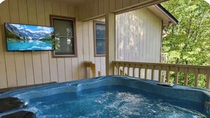 A hot tub on a covered deck with a mountain landscape painting above it. - Peaceful 3BR w Hot Tub, in Rumbling Bald, Lake Lure, Resort amenities included (Lake Lure)