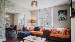 Ein Wohnzimmer mit Sofa, Couchtisch, Lampe und einem Gemälde an der Wand.
