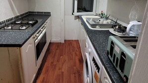 Eine kompakte Küche mit Gasherd, Backofen, Mikrowelle und Waschmaschine.