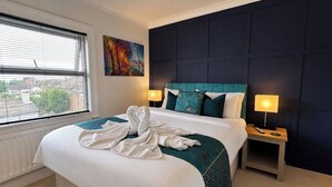Ein Hotelzimmer mit einem großen Bett, zwei Nachttischlampen, einem Bild an der Wand und einem Fenster mit Jalousien.