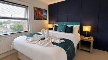 A hotel room with a large bed, two bedside lamps, a painting on the wall, and a window with blinds.