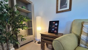 A room with a potted plant, a framed guitar poster, a lamp, and a chair. - Character Bedford Apartment with Two Bedrooms (Bedford)