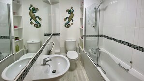 Ein Badezimmer mit zwei Waschbecken, einer Toilette, einer Dusche und dekorativen Wandbildern.