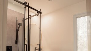 Ein modernes Badezimmer mit einer Duschkabine, einem Holzwaschtisch, einer Toilette und einem Fenster.